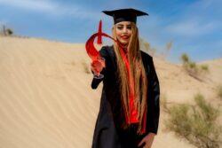 a woman in a graduation gown holding a red object